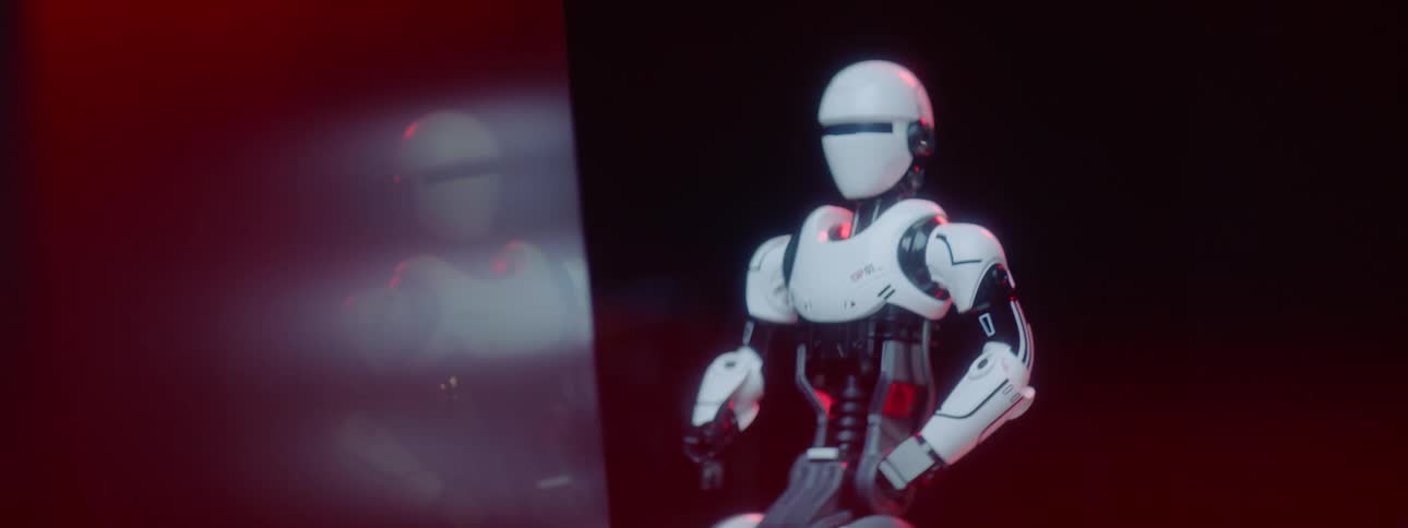 A woman programs and moves a robot with a joystick