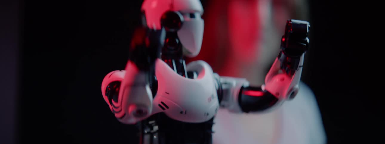 A woman watches a small robot turnin a circle