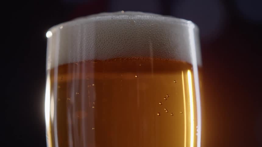 Close up glass of beer with frothy foam at top