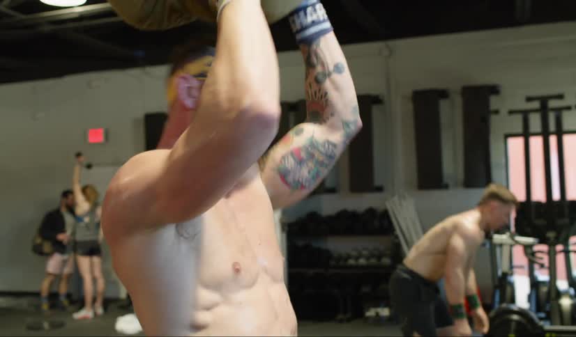 Man exercises using filled sack as weight in gym