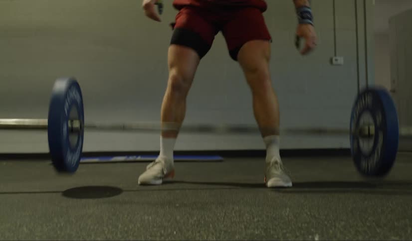 A man lifts a heavy weight over his head then drops it on the gym floor