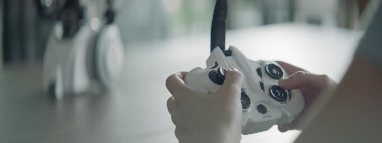 A girl uses a remote control to move a robot