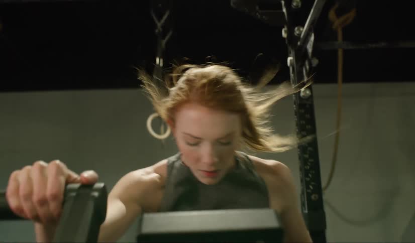 A woman pedals hard on an exercise bike