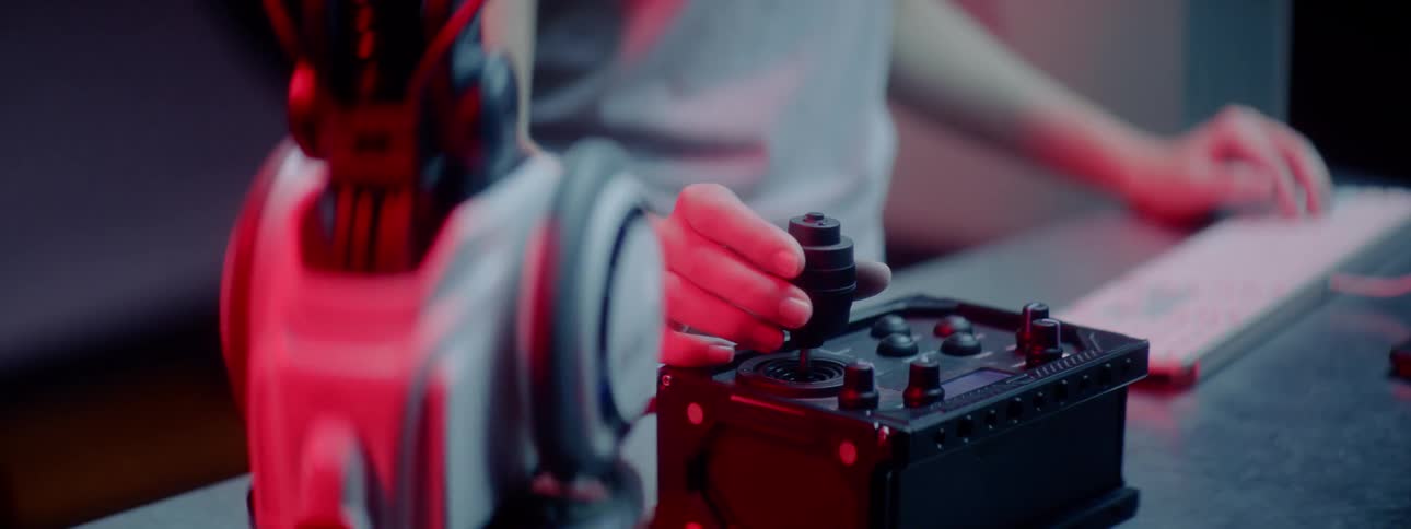 A person in front of a computer keyboard while turning a machine dial