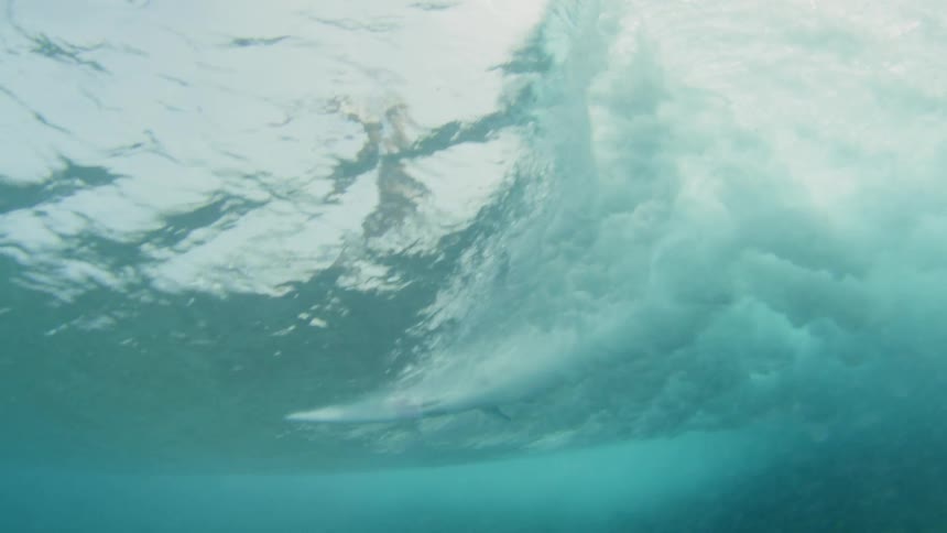 A surfer riding a wave filmed from below