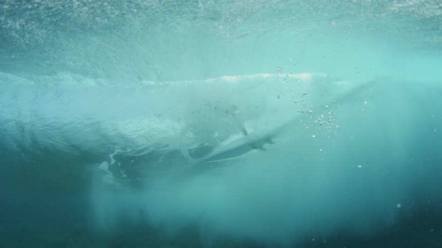 A surfer riding a wave seen from underwater