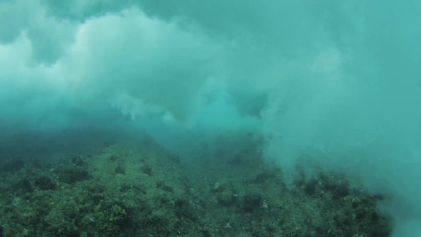 Underwater footage of waves crashing on coral reef coast