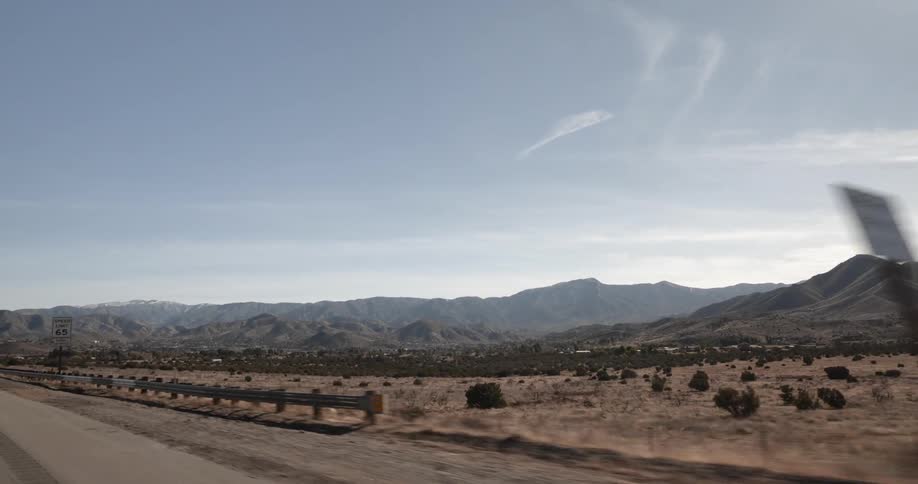 Driving down a highway past desert mountains