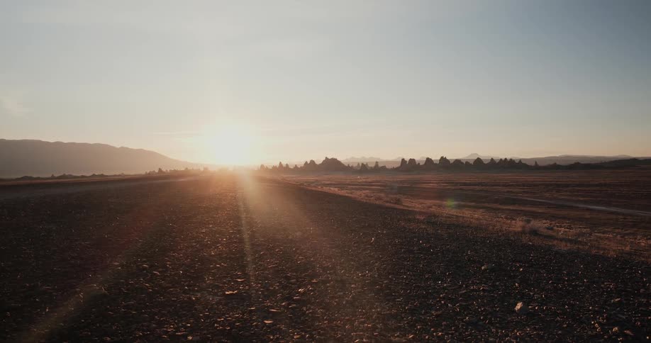 A long dirt road with the sun setting on the horizon