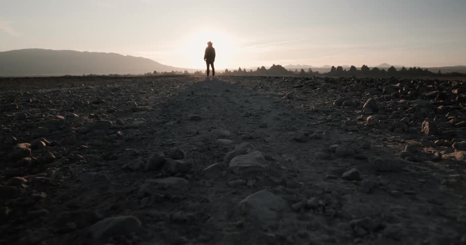 A person stands alone on top of a rocky terrain looking towards the horizon
