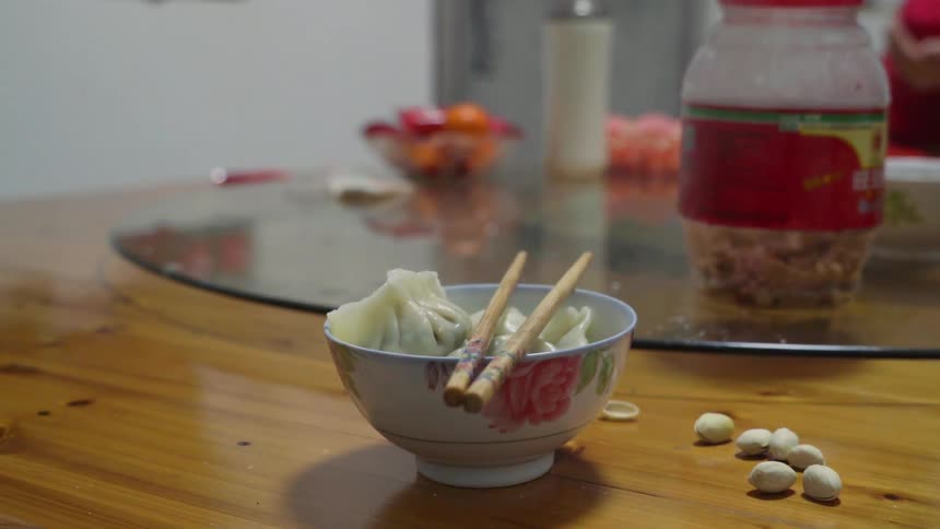 Wooden chopsticks resting atop a bowl of steaming dumplings