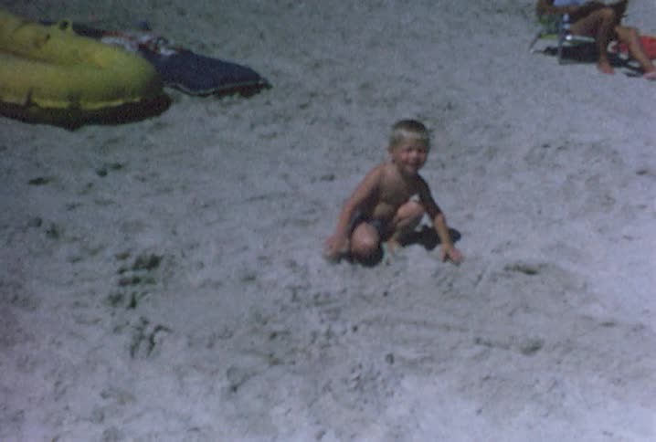 A boy is playing on the sand of a beach