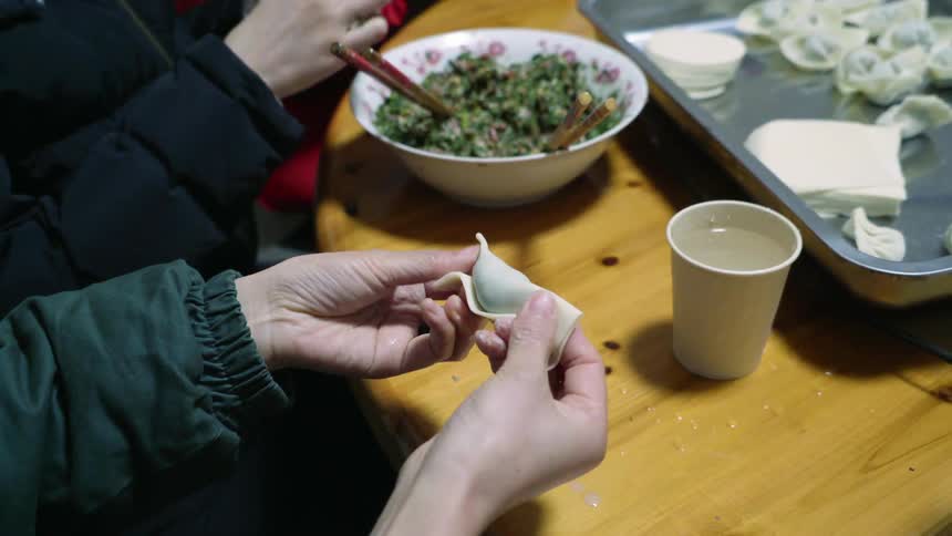 Hands stuffing and wrapping wontons