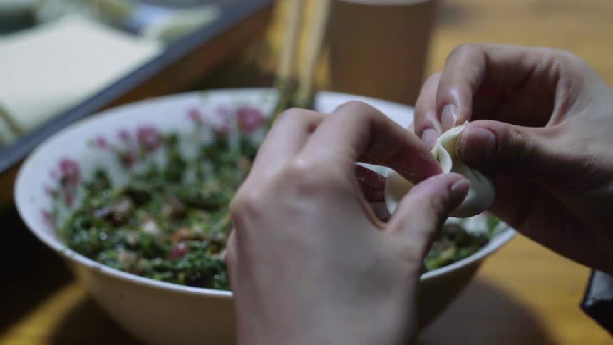 A person is preparing dumplings using bare hands