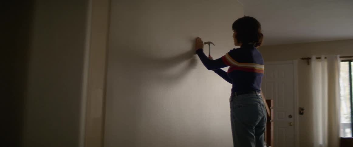 A woman hammers a nail in to a wall