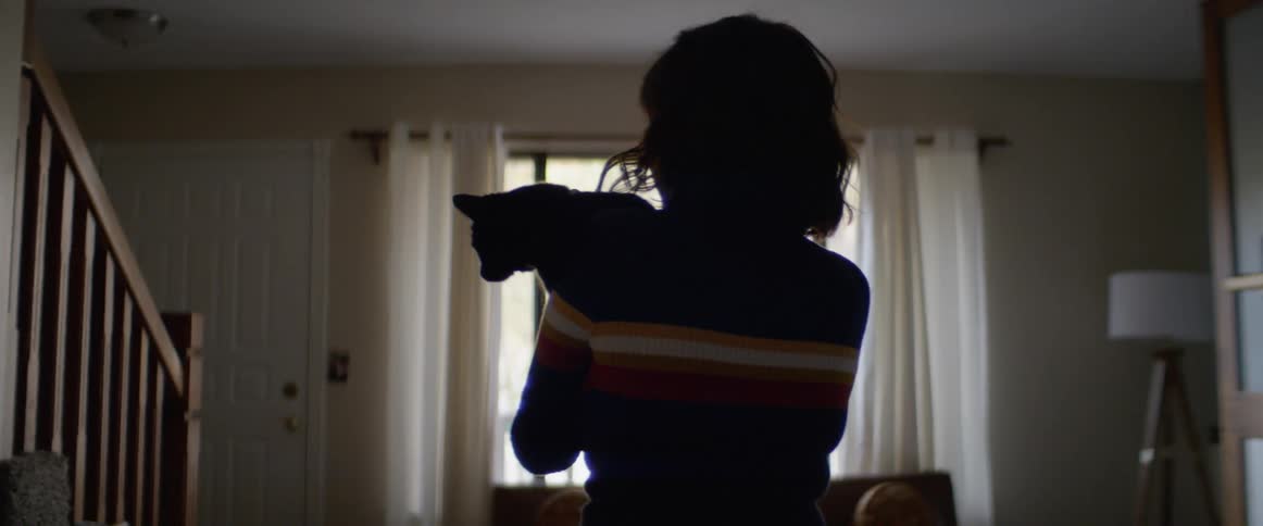 A woman carries her cat through the house
