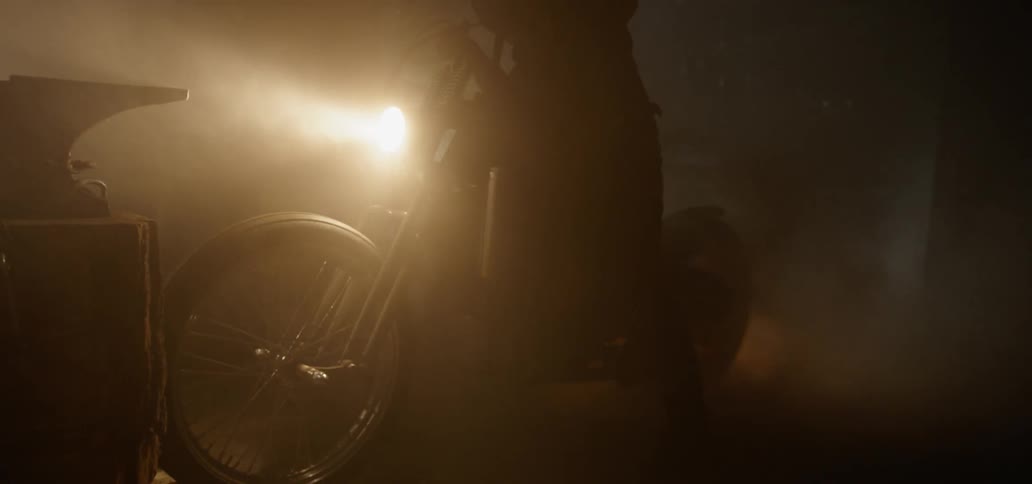 A person is sitting on a motorcycle at night in smoke filled air