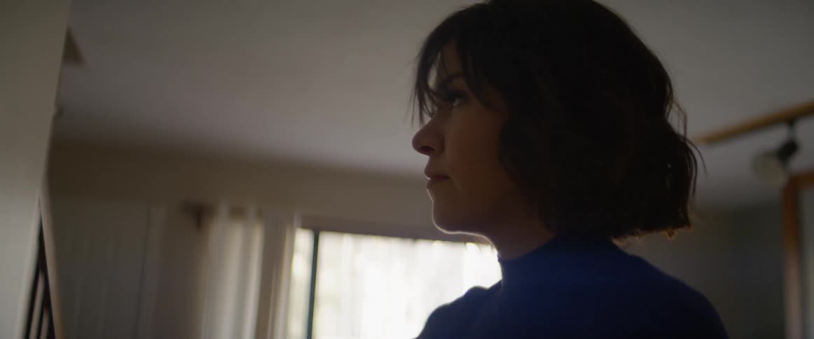 A woman straightens something on a wall in a room