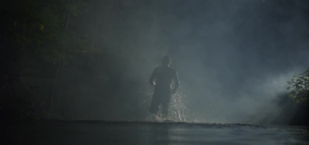 Man running through fog down a river at night