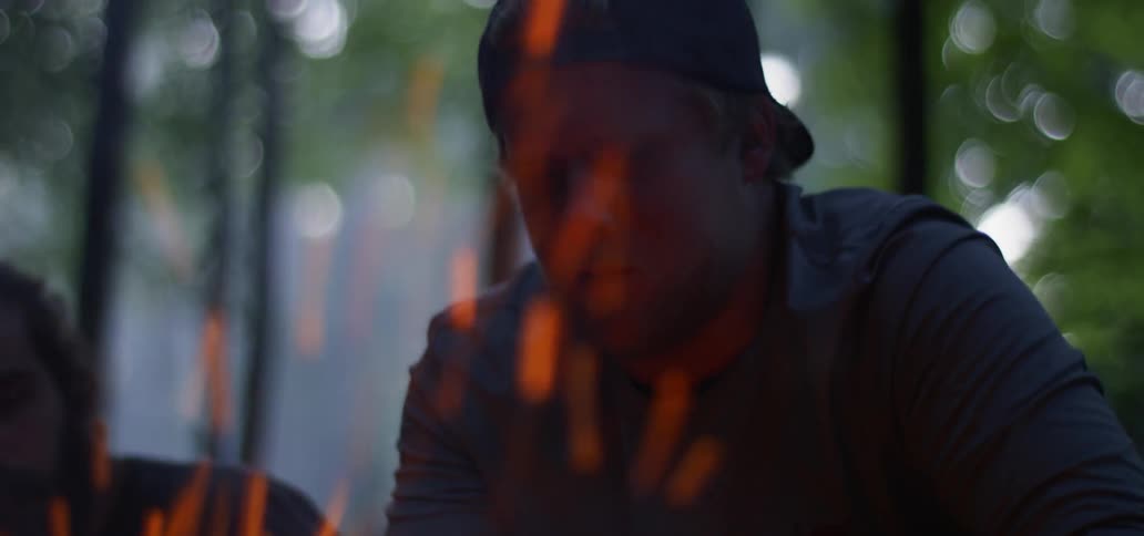 Two men sit around a fire