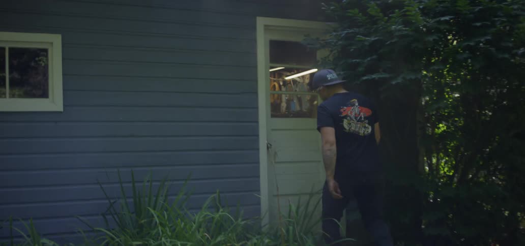 Man walks through backyard and enters tool shack