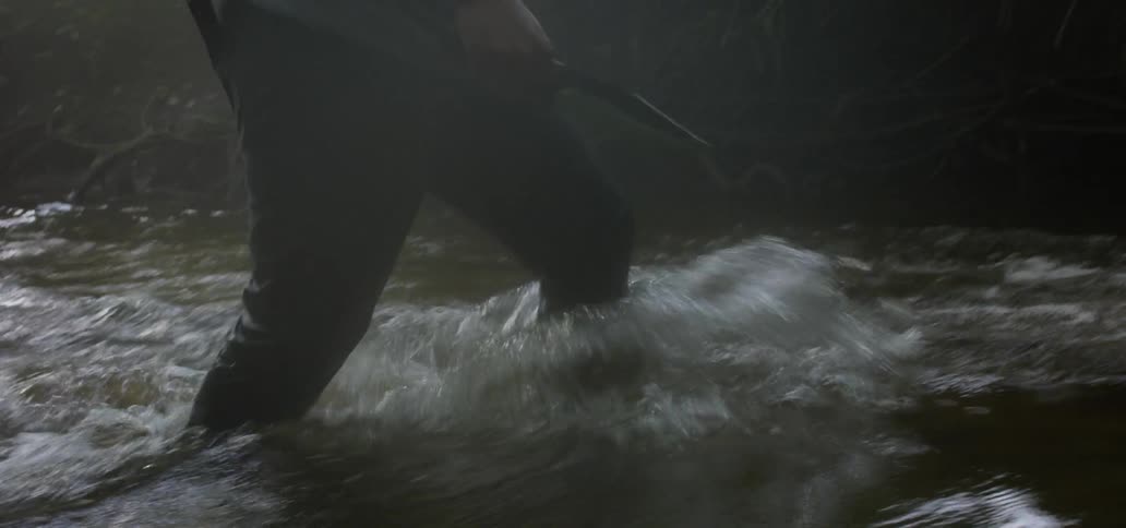People walking on a river with knives and a rifle
