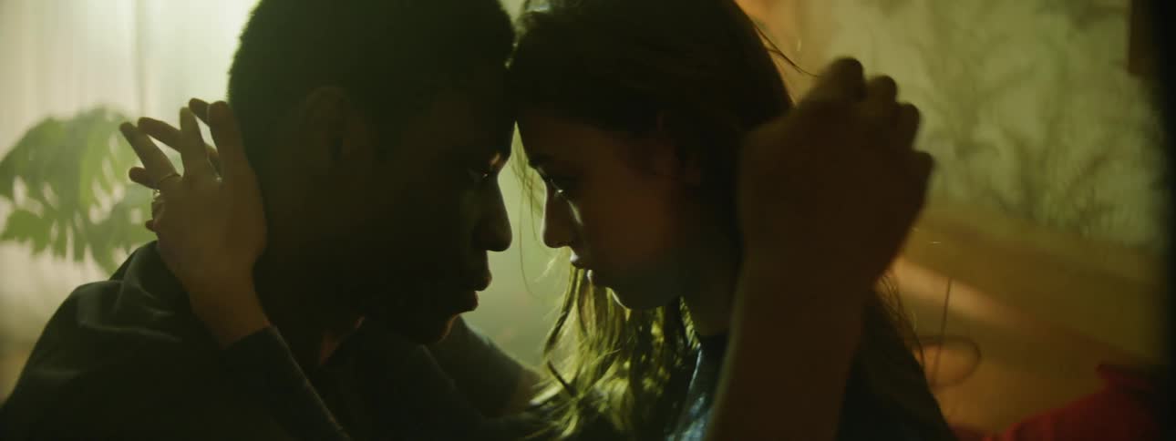 A male and female put their heads together to kiss