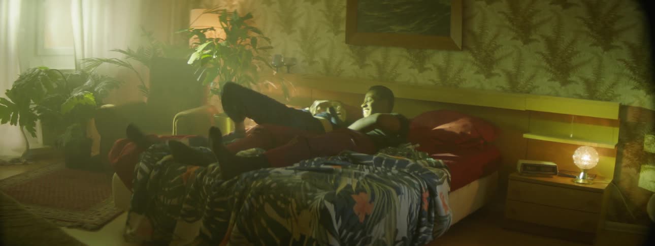 A man and woman cuddle and tickle each other on a bed in a hotel room