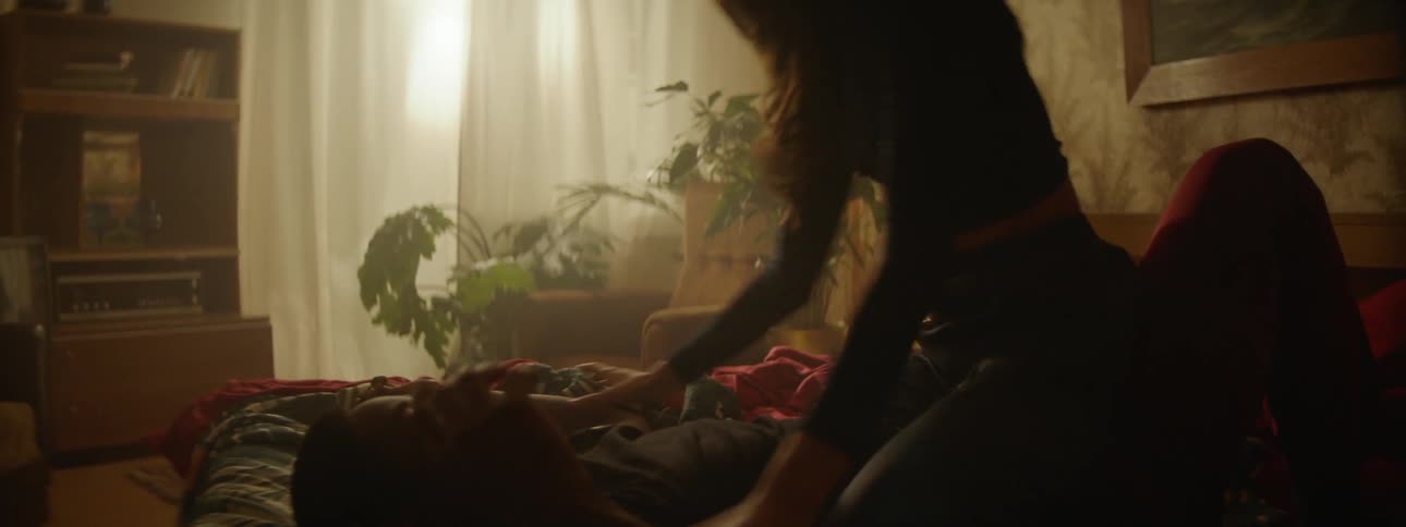 A couple frolicking on a bed as the sun streams through the window