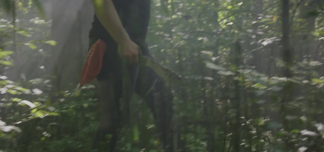 A man walking through a forest carrying a kukri