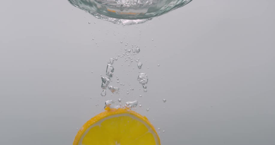 Orange slice falling down the water