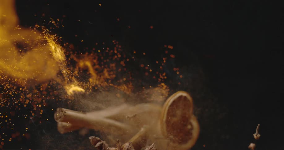 A flame is emitted over some potpourri in a darkened room which creates sparks and embers