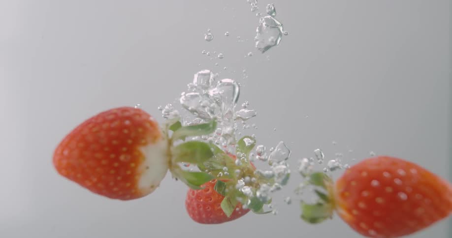 Strawberries falling down the water
