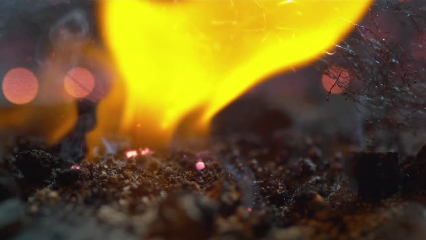 A flame rises from hot burning embers