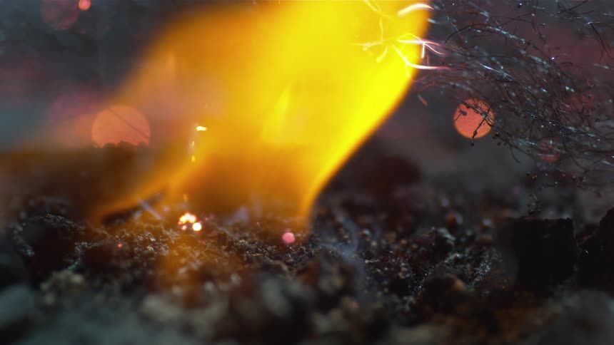 A flame burns atop a pile of charcoal powder which creates small sparks and embers