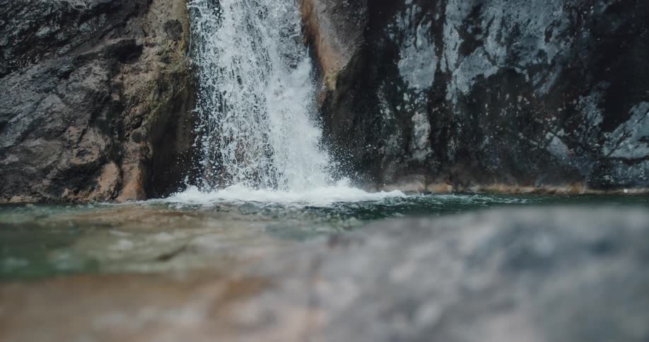 Waterfall splashes down cliffside into pool creating turbulence