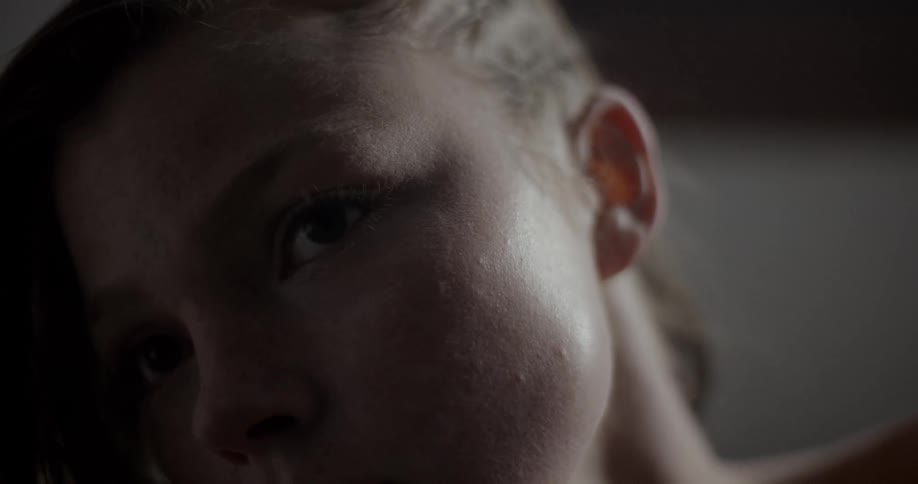 A young woman tilts her head to the side as she looks attentively off into the distance