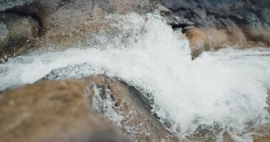 Slow motion view of water flowing over rocks in a canyon