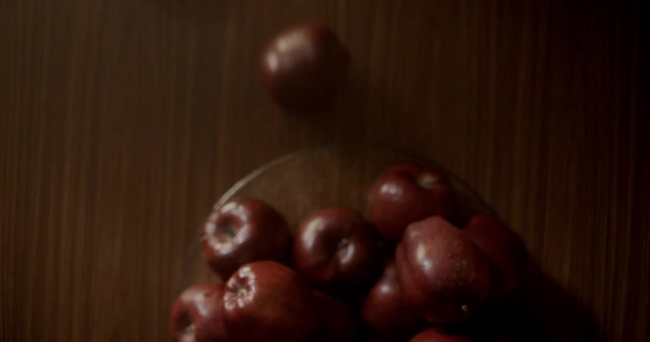 Apples falling on table from a container after someone bangs the table