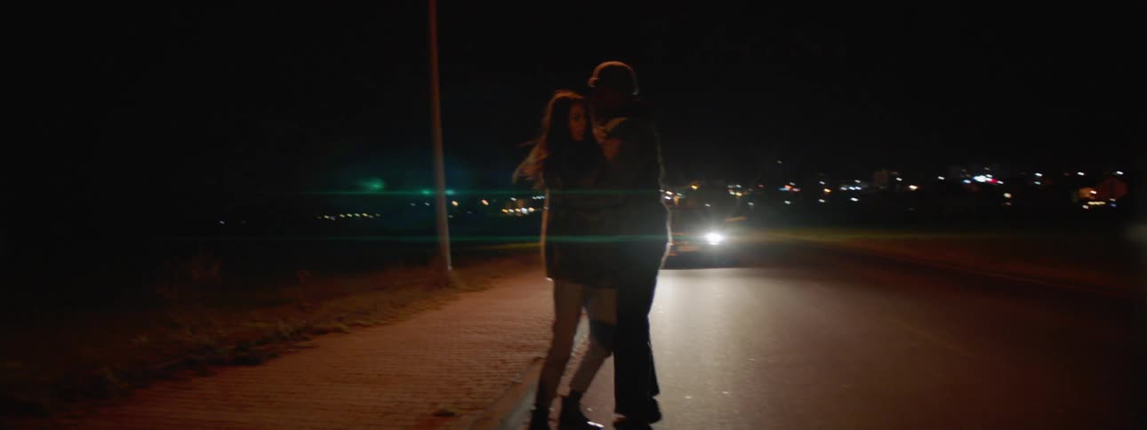Man and woman scuffle as they walk on the road at night