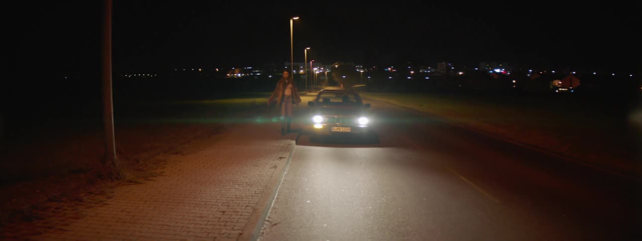 A car driving at night pulls over and the female passenger defiantly exits only to be chased down by the male driver
