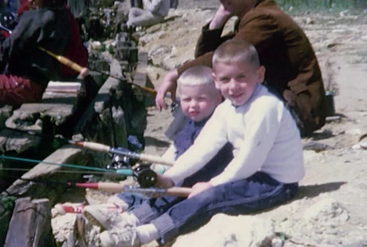 Old footage of people fishing from a sea wall that focuses in on two little boys and then a girl