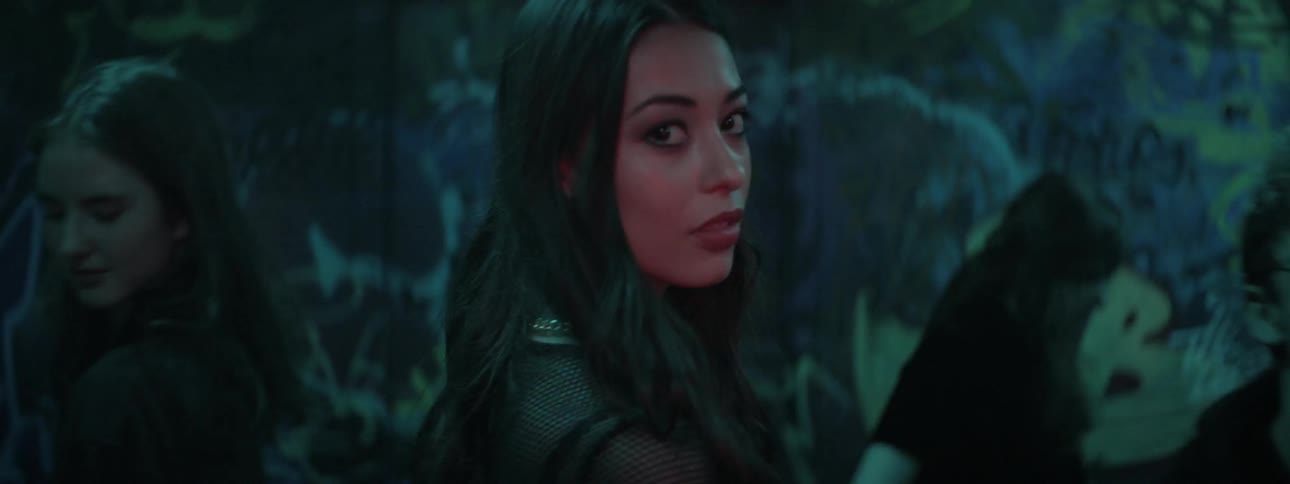 Woman walks through a party and looks at camera in a nightclub