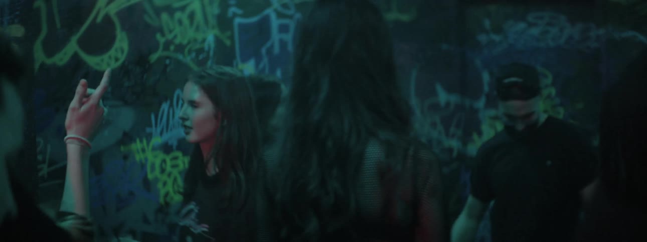 A woman walks through a group of people dancing at a night club