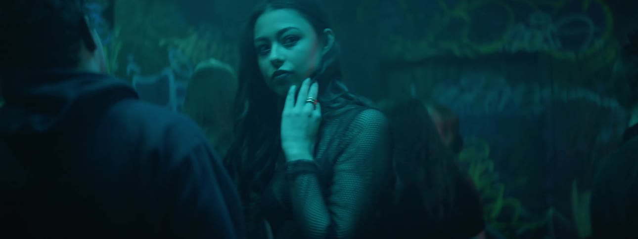 A young woman dances with a young man in a darkened dance club with strobing lights
