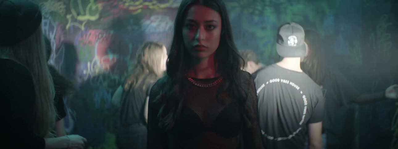 White woman walking in the middle of people dancing at a night club
