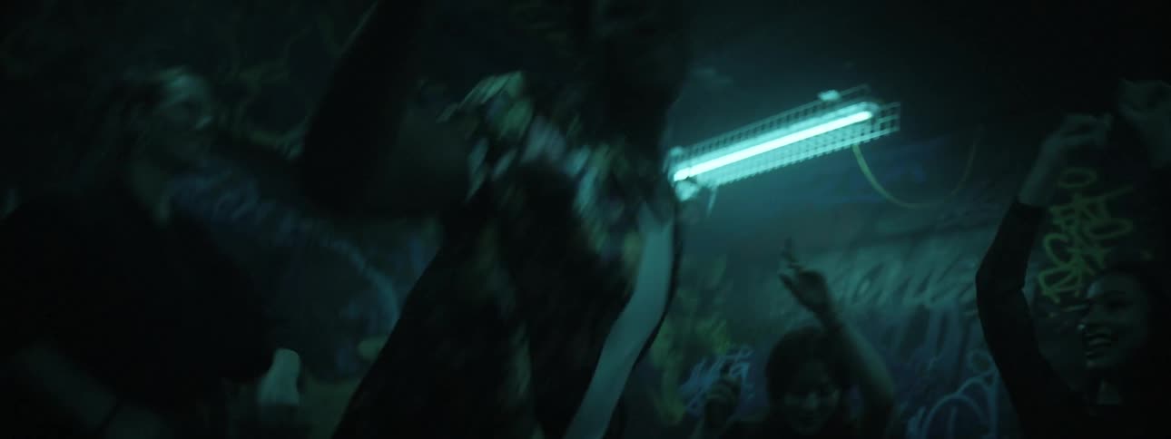 Teenagers dance while lights flash around them
