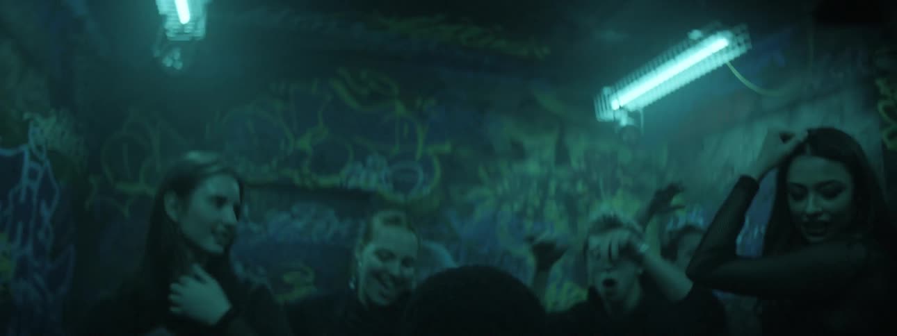 Young people dancing in a room with graffiti covered walls