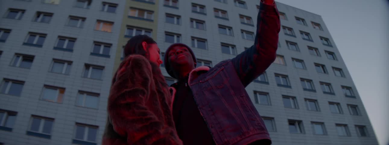 A man and woman stand outside and take a selfie together