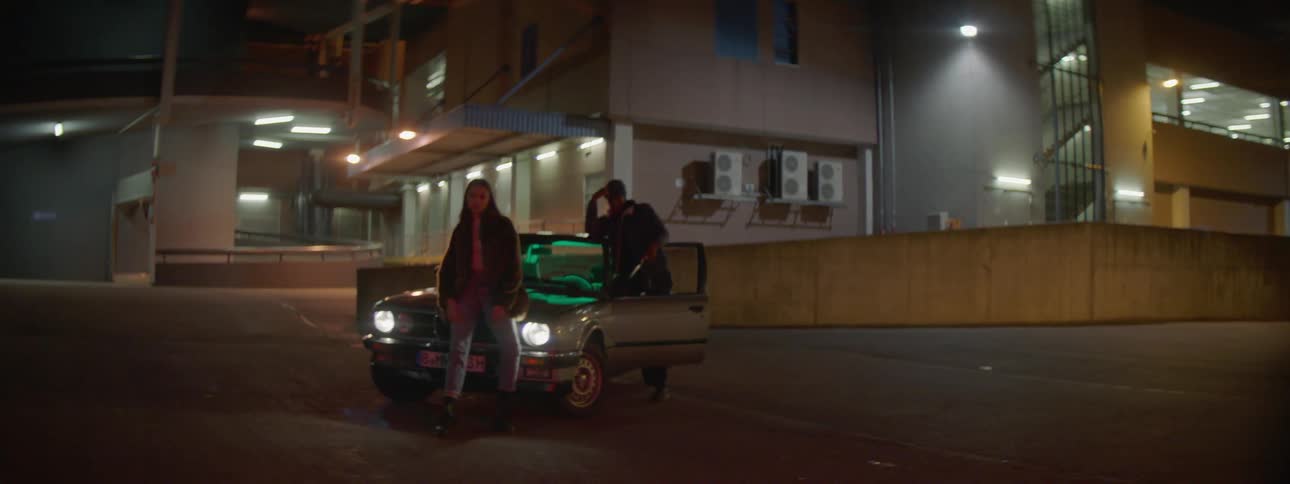 Couple standing outside car on a city street at night